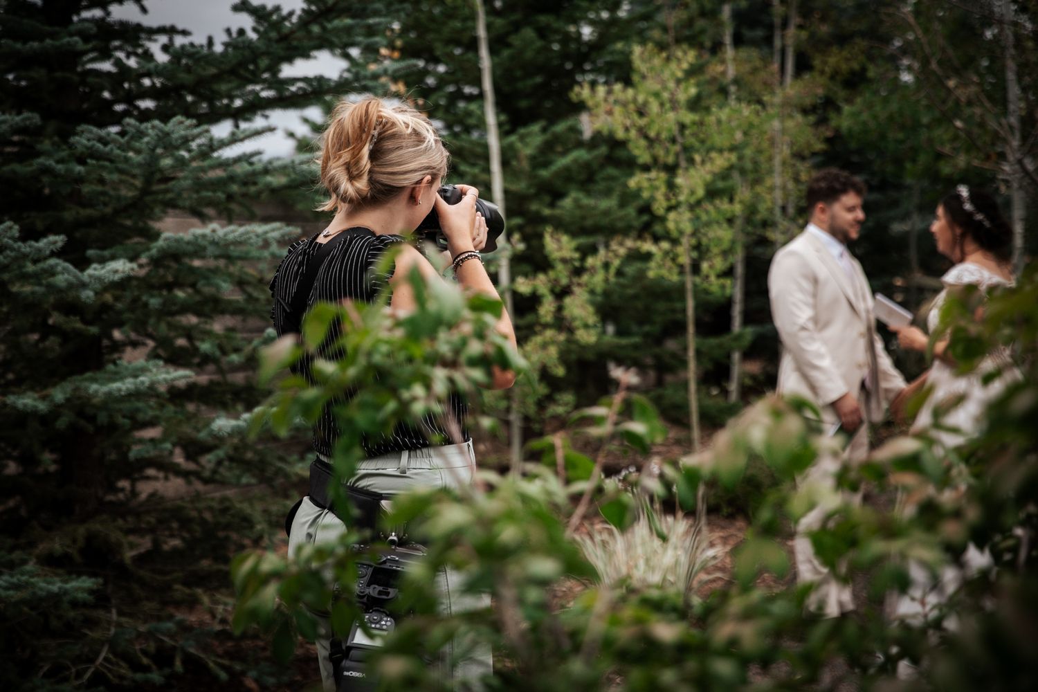 Rachel McNurlen photographing a couple through the trees at a mountain wedding